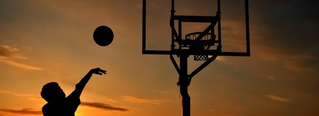 Silhouette of Teen Boy Shooting a Basketball at Sunset, copy space